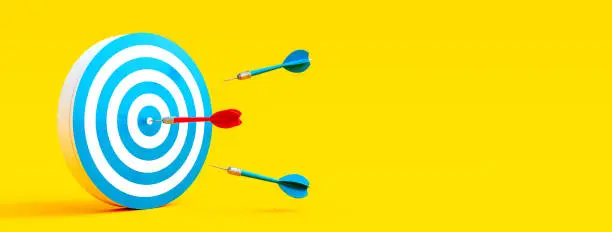 Photo of Red dart finding the target. Business solution concept on yellow background