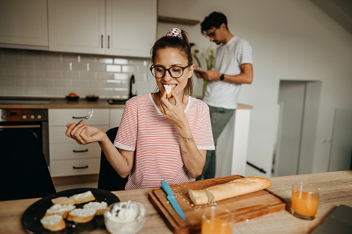 Young couple preparing breakfast and eating in kitchen