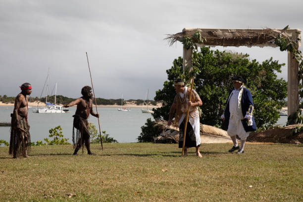 gli aborigeni australiani in abito nativo si esibiscono in una rievocazione storica dell'arrivo del capitano james cook in australia al fiume endeavour 250 anni fa. cooktown, queensland, australia - indigenous culture australia aborigine australian culture foto e immagini stock