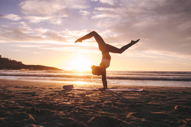 femme faisant du yoga pose handstand sur la plage - inversion yoga photos et images de collection