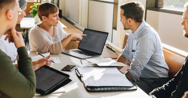 dirigente femminile che mostra i dati al team in riunione - finance foto e immagini stock