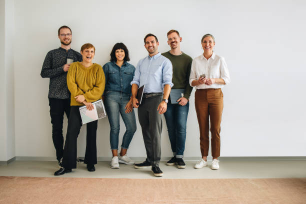 istock Happy colleagues standing against wall in office 1323324778
