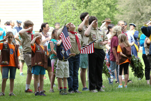 boy scouts y girl scouts saludando en la ceremonia del día de los caídos celebrada en lexington, ma el martes, domingo, 24 de mayo de 2015 - child patriotism saluting flag fotografías e imágenes de stock