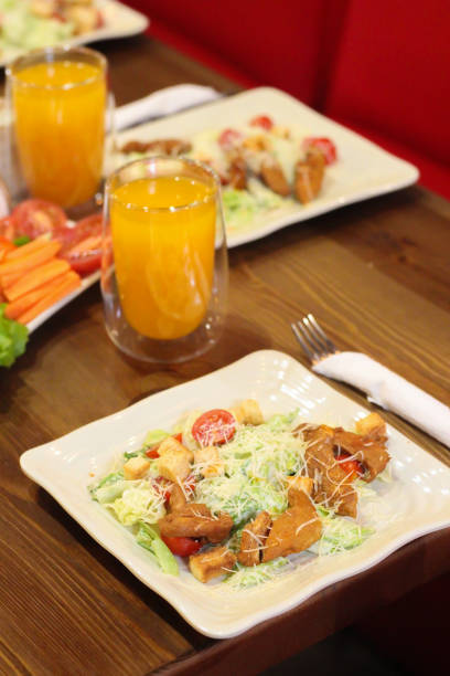 istock Caesar salad in the restaurant and orange juice. Caesar salad with chicken 1323326995