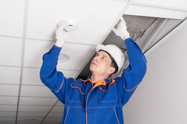 istock a worker installs a smoke and fire detector on the ceiling in the office 1323327007