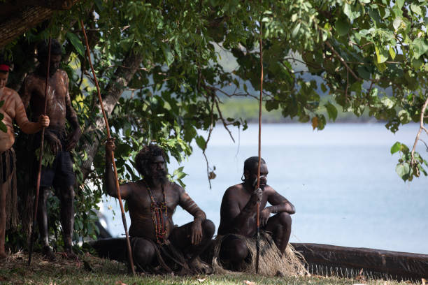 gli aborigeni australiani in abito nativo si esibiscono in una rievocazione storica dell'arrivo del capitano james cook in australia al fiume endeavour 250 anni fa. cooktown, queensland, australia - indigenous culture australia aborigine australian culture foto e immagini stock