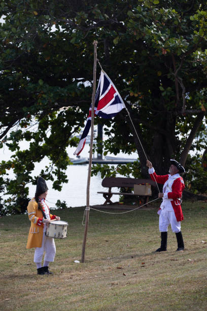 alzando bandiera britannica in australia durante la rievocazione dello sbarco del tenente james cook a waalmbal birri (fiume endeavour) e incontri con il guugu yimithirr bama nel 1770. il 250 ° anniversario del primo contatto dell'australia, cooktown, que - indigenous culture australia aborigine australian culture foto e immagini stock