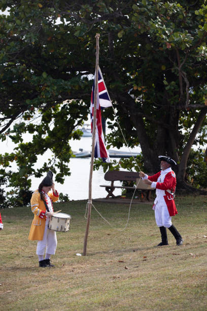 alzando bandiera britannica in australia durante la rievocazione dello sbarco del tenente james cook a waalmbal birri (fiume endeavour) e incontri con il guugu yimithirr bama nel 1770. il 250 ° anniversario del primo contatto dell'australia, cooktown, que - indigenous culture australia aborigine australian culture foto e immagini stock