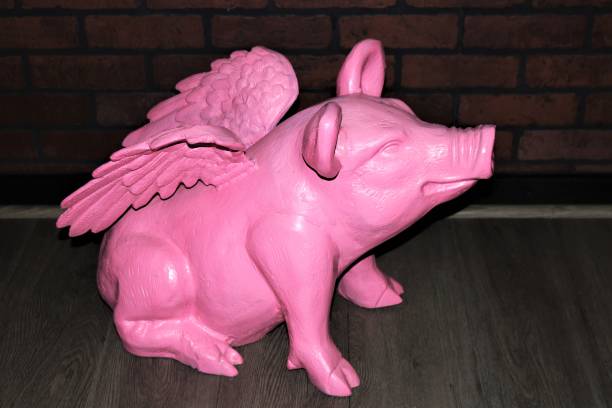 istock Pink Ceramic Pig with Wings Sitting on Wood Floor 1323328349