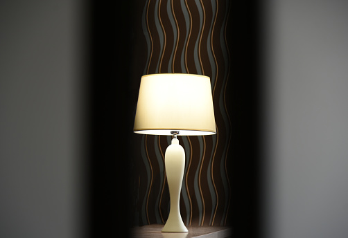 Table lamp dimly shines on the table in the bedroom.