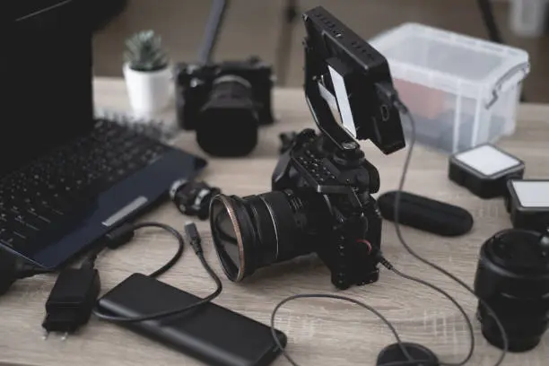 Photo of top view of work space photographer with digital camera, flash, cleaning kit, memory card, tripod and camera accessory on black table background
