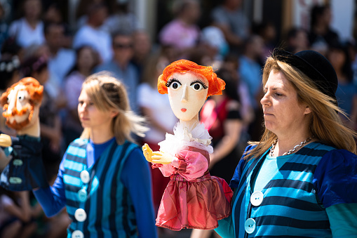 Kazanlak, Bulgaria - June 6, 2021: Women holding puppets during the annual Kazanlak Rose Festival parade when folklore groups local artists music bands and students show their creative abilities during a march through the center of the city