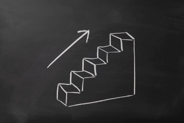 Stairs heading upwards with an arrow drawn on a black chalkboard.