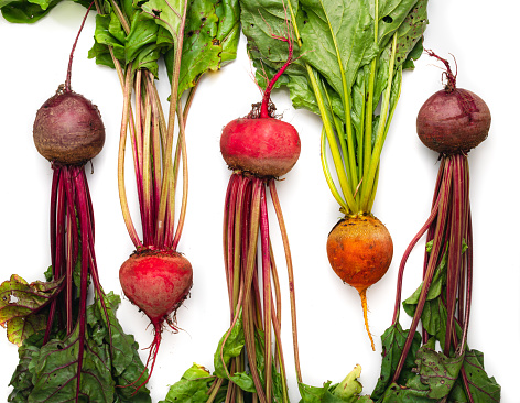 Beet roots of different colors on a white table.