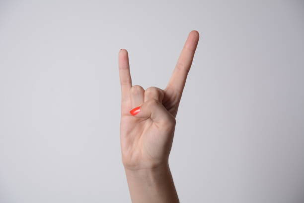 mano de mujer que muestra el gesto de los cuernos del diablo. signo ganador y triunfal aislado sobre fondo blanco. - roll of arms fotografías e imágenes de stock