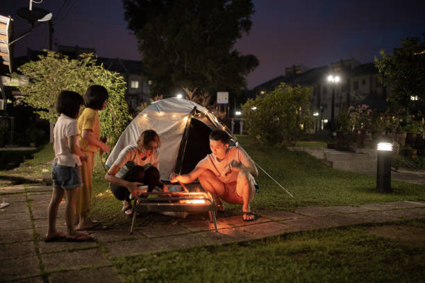 des parents chinois d’origine asiatique installent un camp de camping dans la cour arrière de leur maison des activités du week-end de séjour - camping family tent couple photos et images de collection