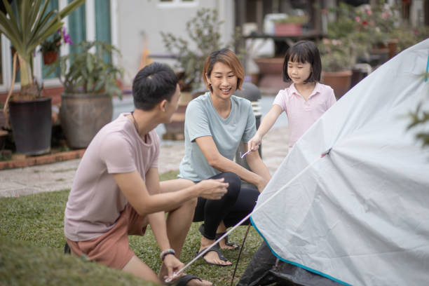 Asian Chinese father setting up camping tent together with family at backyard Asian Chinese father setting up camping tent together with family at backyard hit the nail on the head stock pictures, royalty-free photos & images