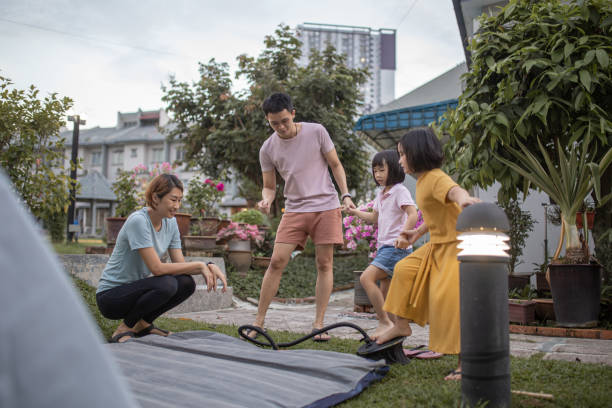 istock Asian Chinese sibling helping parent setting up tent camping at backyard 1323343936