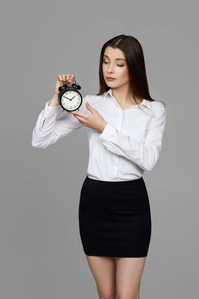 belle femme d’affaires caucasienne tenant un réveil - clock face alarm clock clock minute hand photos et images de collection