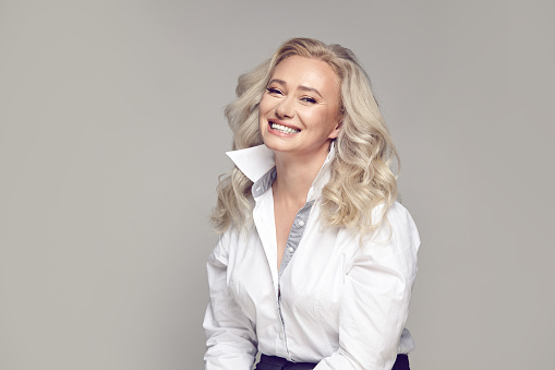 Close up portrait, happy older lady wearing in stylish casual clothing smiling on a gray isolated background