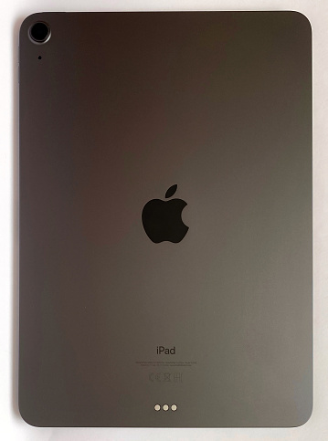 The iPad Air 2020 tablet in black color lies on a branded box on a white isolated background. Back side view of the tablet.