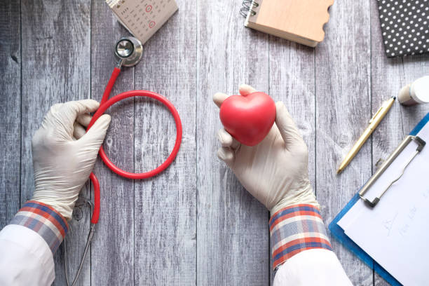 istock doctor hand holding red heart and stethoscope on table 1323352032