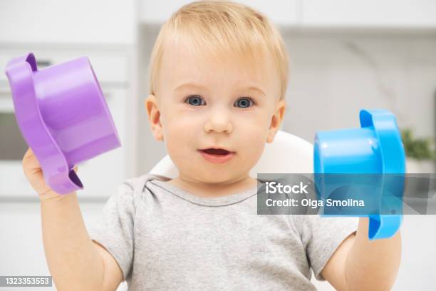 Happy Caucasian Blonde Baby Girl Playing With Toys Looking At Camera Kid Sitting At Highchair In Kitchen Idea Of Child Early Development Stock Photo - Download Image Now