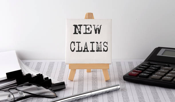 istock text NEW CLAIMS on easel with office tools and paper.Top view. 1323355774