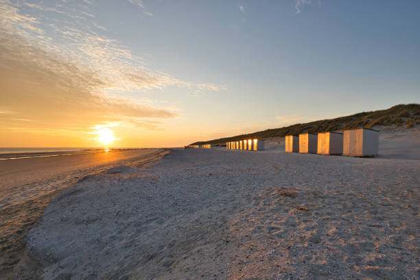 istock Horizontal view on a beach with a row of beach cabins at sunset in spring. 1323358845