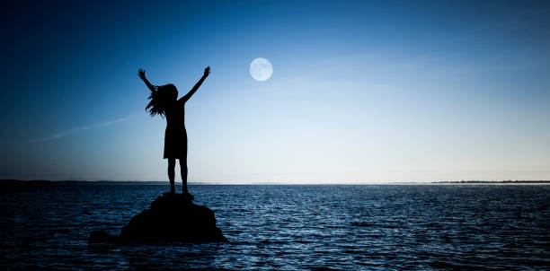Woman on a rock in the water during a full moon Woman on a rock in the water during a full moon full moon photos stock pictures, royalty-free photos & images