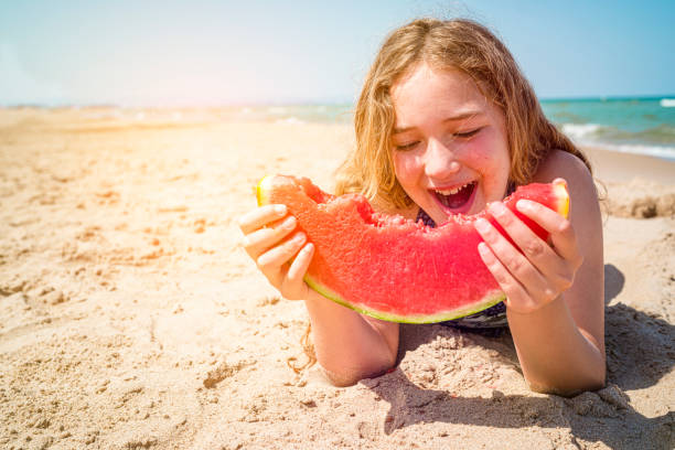 istock Girl eating watermelon at the beach 1323366566