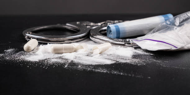 handschellen mit drogen auf dem tisch nahaufnahme, konzept von recht und drogen - narcotic drug abuse cocaine heroin stock-fotos und bilder