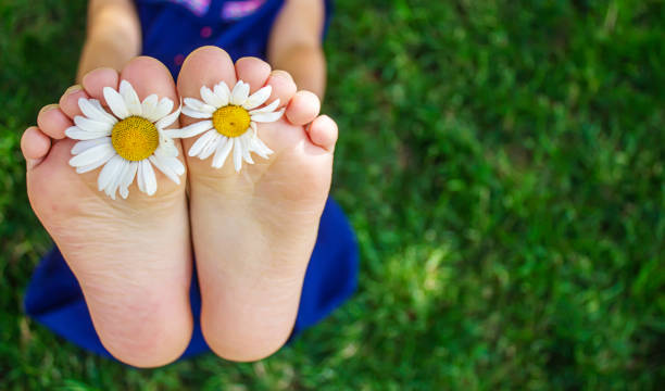 istock Children's feet with chamomile on green grass. Selective focus. 1323368257
