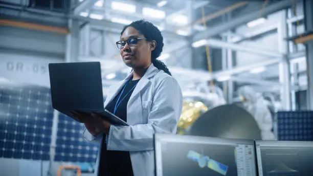 Photo of Portrait of Brilliant Female Engineer Confident and Focused Thinking, working at Aerospace Satellite Manufacturing Facility. Top World Scientist Doing Science and Technology Research in Space Program