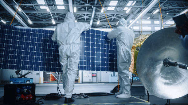 ingeniero y técnico en trajes de protección trabajando en la construcción de satélites. aerospace agency: team of scientists fixing solar panel wings to spacecraft. misión internacional de exploración espacial - voyager nave espacial fotografías e imágenes de stock