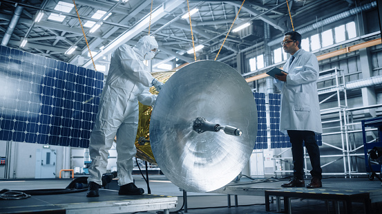 Engineer and Technician Working on Satellite Construction. Aerospace Agency Spaceship Manufacturing Factory: Diverse Group of Scientists Developing Spacecraft. International Space Exploration Program
