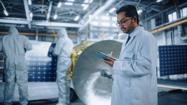istock Team of Engineers Working on Satellite Construction, Scientist Uses Tablet Computer. Aerospace Agency: Diverse Group of Specialists Developing Spacecraft for Space Exploration Mission 1323369515
