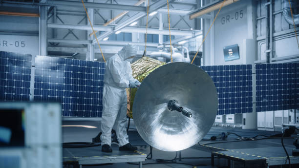 istock Engineer in Protective Suit Working on Satellite Construction. Aerospace Agency Manufacturing Facility: Scientists Developing Spacecraft for Space Exploration, Communications, Cosmos Observation 1323369588