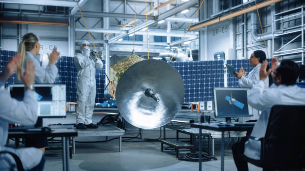 istock Technician in Protective Suit Finishes Satellite Construction, Team of Scientists Applaud and Cheer for Successful. Aerospace Agency Manufacturing Facility: Scientists Assembling Spacecraft. 1323369623