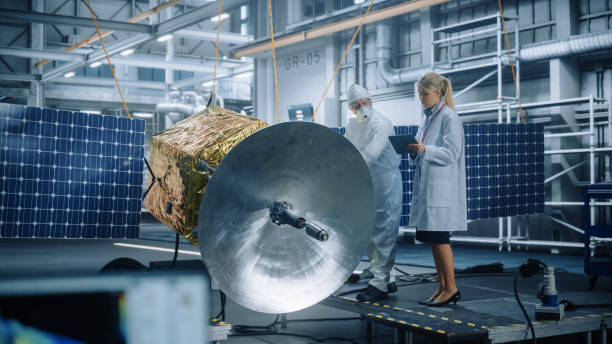 istock Female Chief Engineer talk to Technician while he is Working on Satellite Construction. Aerospace Agency Manufacturing Facility: Scientists Build, Assemble Spacecraft for Space Exploration Mission 1323369654