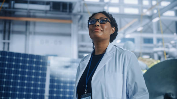 brilliant female engineer looking around in wonder at the aerospace satellite manufacturing facility. young talent starting her career in world top science and technology space exploration program - cientista imagens e fotografias de stock