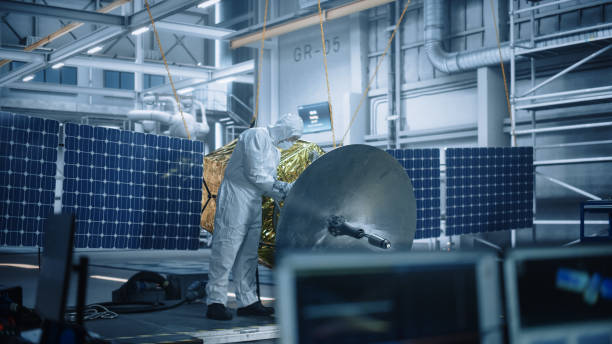 istock Engineer in Protective Suit Working on Satellite Construction. Aerospace Agency Manufacturing Facility: Scientists Developing Spacecraft for Space Exploration, Communications, Cosmos Observation 1323369733