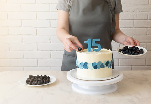 the chef decorates the cake with blueberries and blackberries. cake for 15th birthday, anniversary.