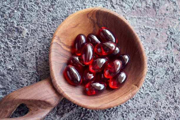 Red krill oil soft gel capsules on a spoon, top view