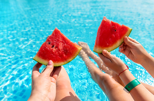 Mother and child eat watermelon near the pool. Selective focus. Food.
