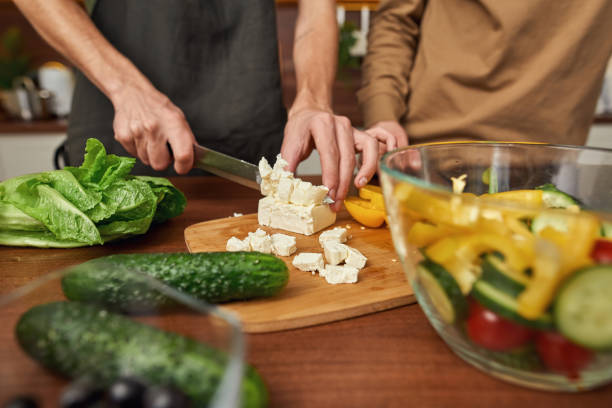 istock Man cutting cheese for salad while cooking 1323380795