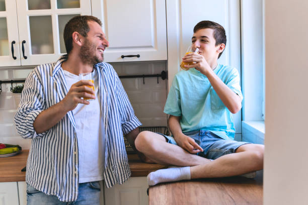 istock Father talking to his teenage son while drinking juice in the kitchen. 1323381810