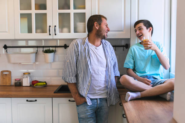 istock Father talking to his teenage son while drinking juice in the kitchen. 1323381816