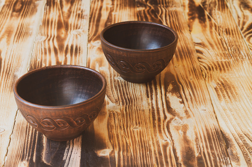 Two empty earthenware bowls on a brown wood table.