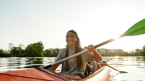 Active young woman smiling, enjoying a day kayaking together with her boyfriend in a lake on a late summer afternoon. Kayaking, travel, leisure concept. Web Banner